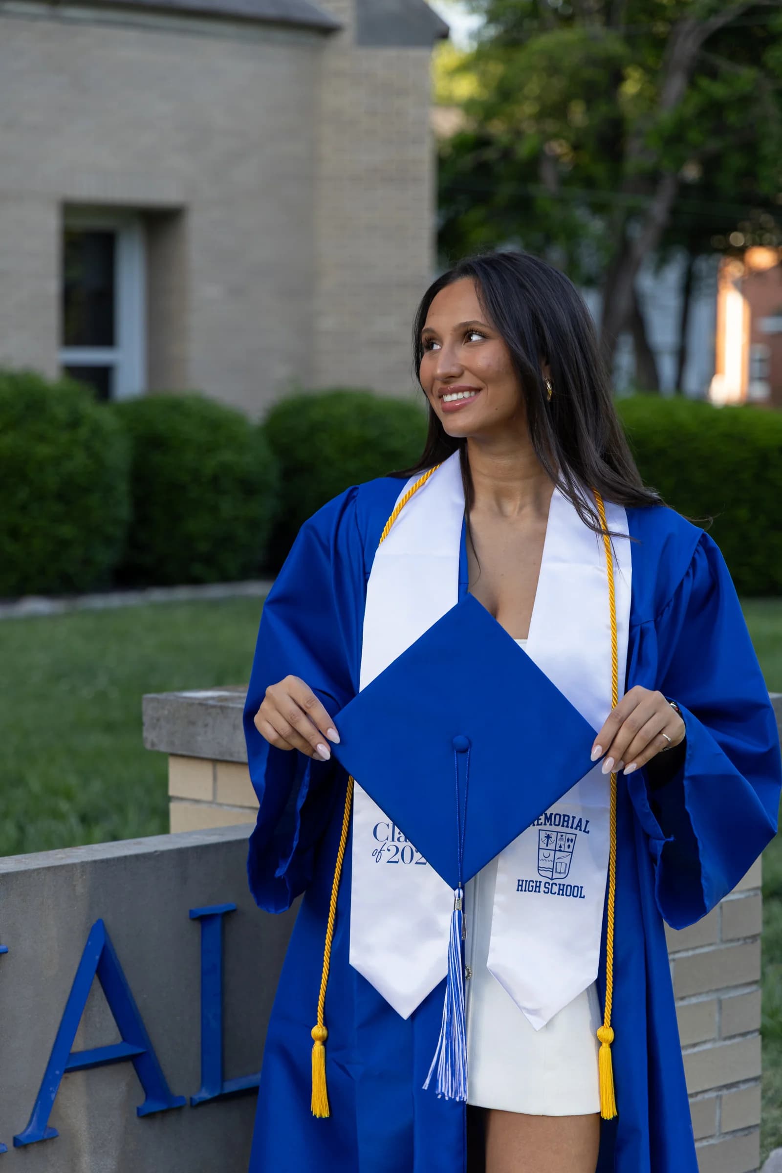 Elizabet holding her graduation cap in a blue gown