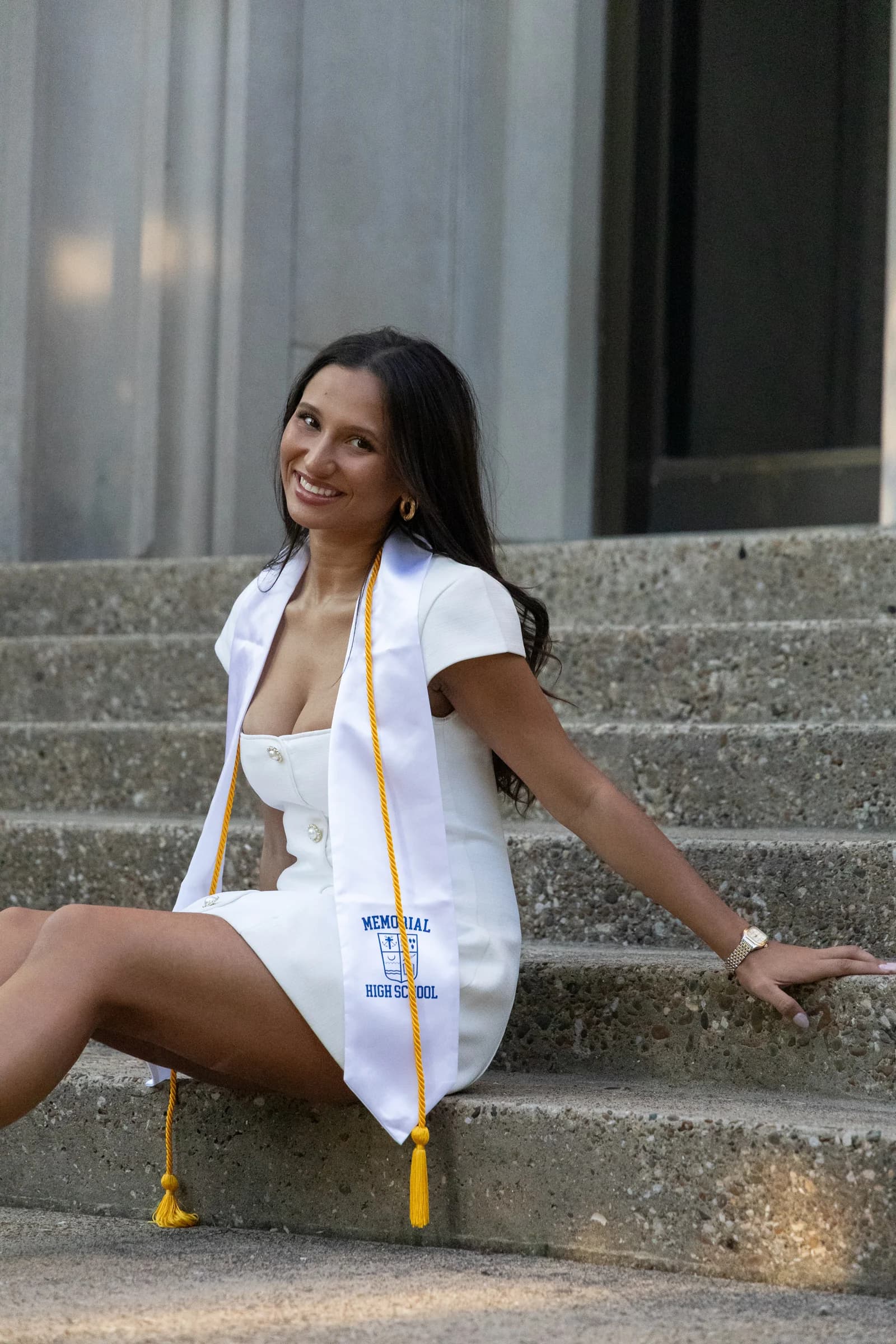 Elizabet seated on the steps wearing her graduation stole