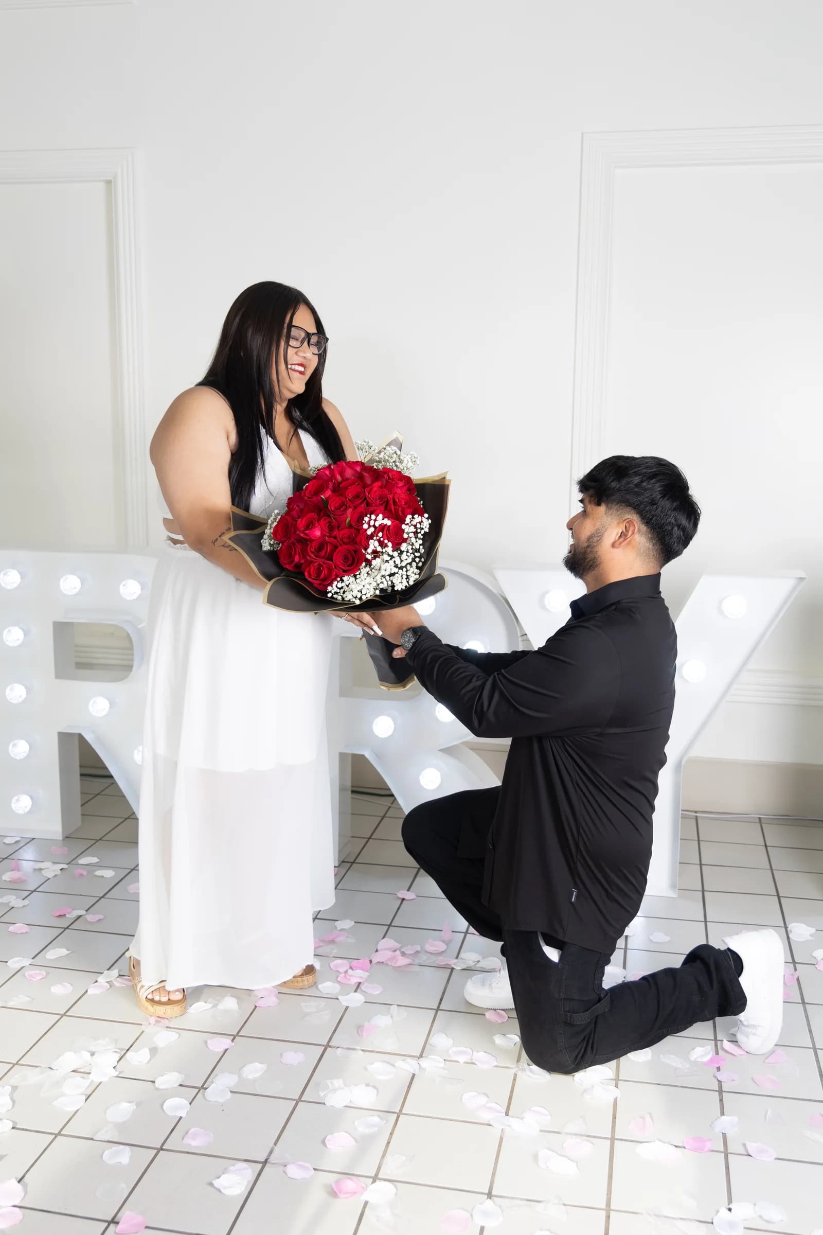 A man kneeling and offering roses to his partner during his proposal
