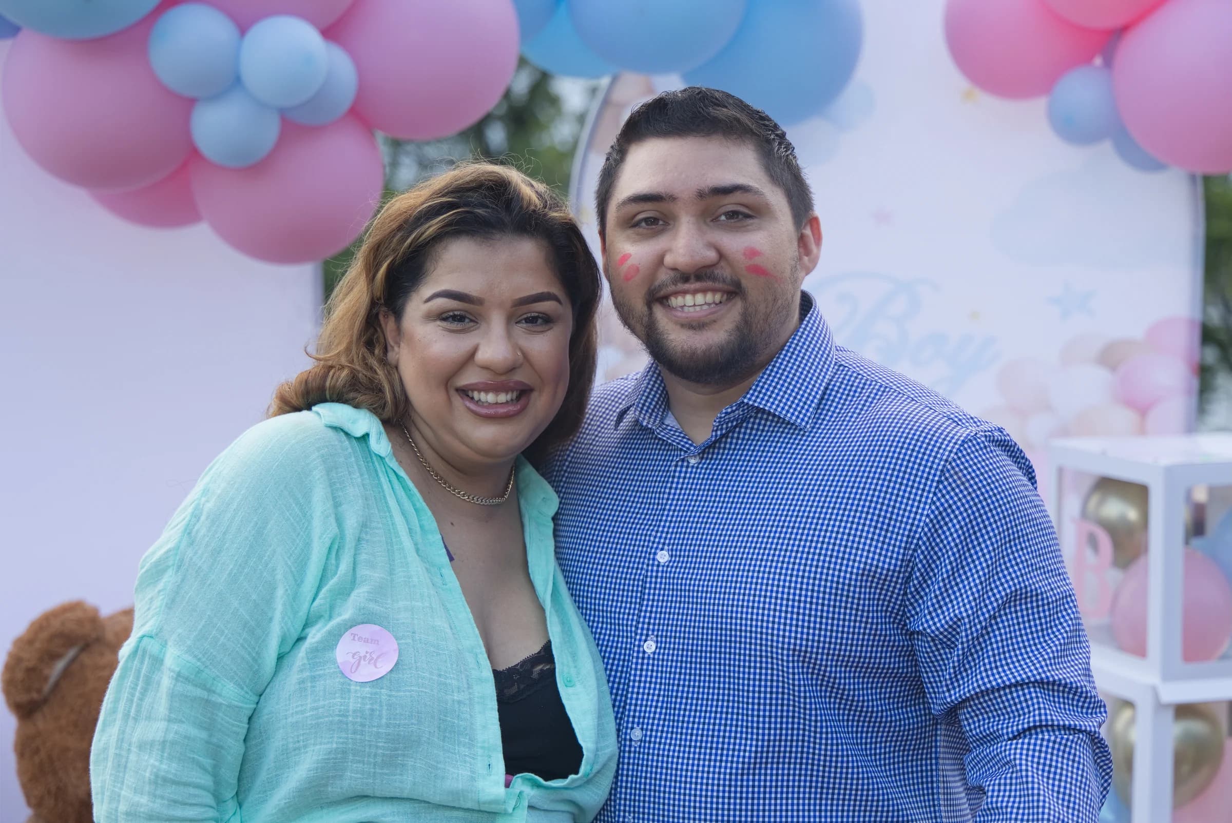 Couple smiling at a family celebration with pink and blue balloons