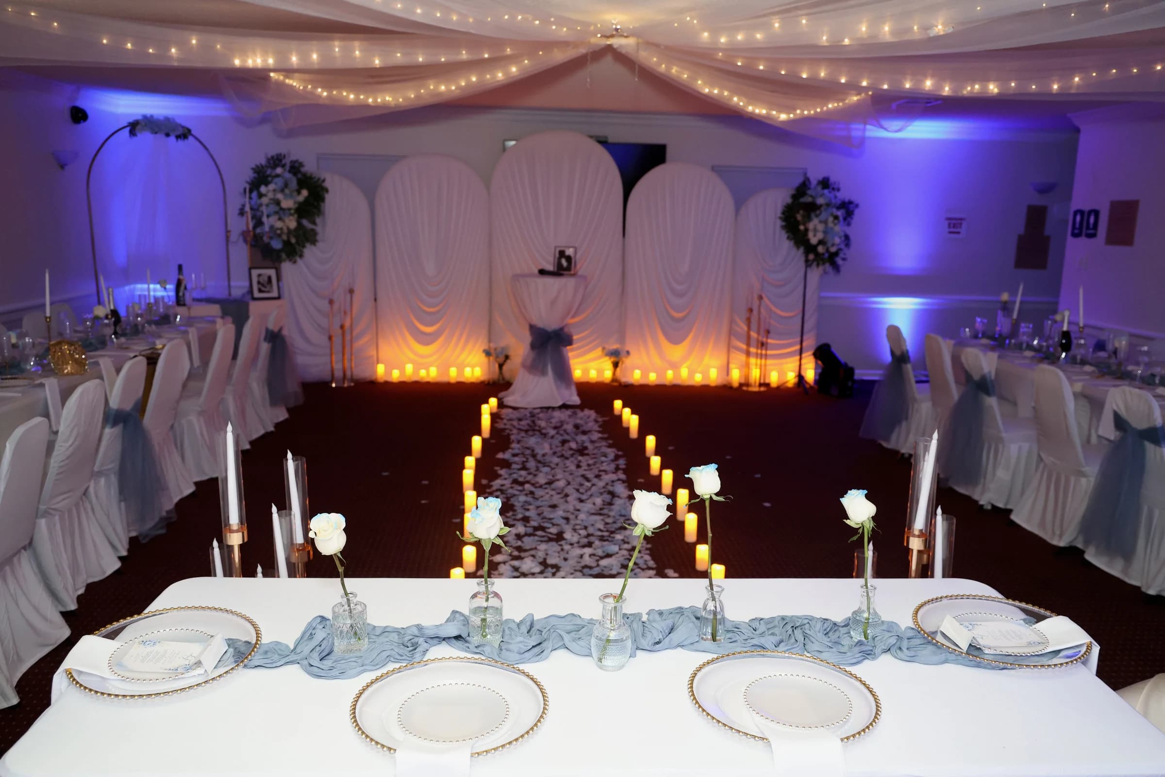 Wedding reception with white flowers, candles and violet lighting